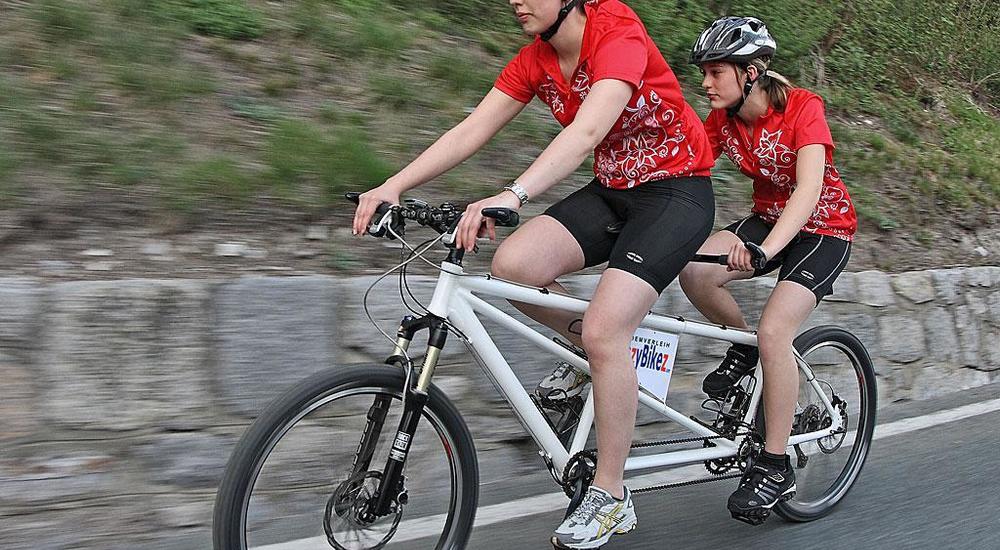 Immagine di due ciclisti in sella ad un tandem mentre pedalano