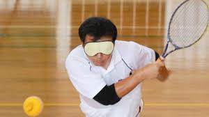 Immagine di un giocatore non vedente che colpisce al volo una pallina sonora con la racchetta da tennis