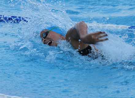 Immagine di un atleta non vedente che nuota all'interno di una piscina olimpionica